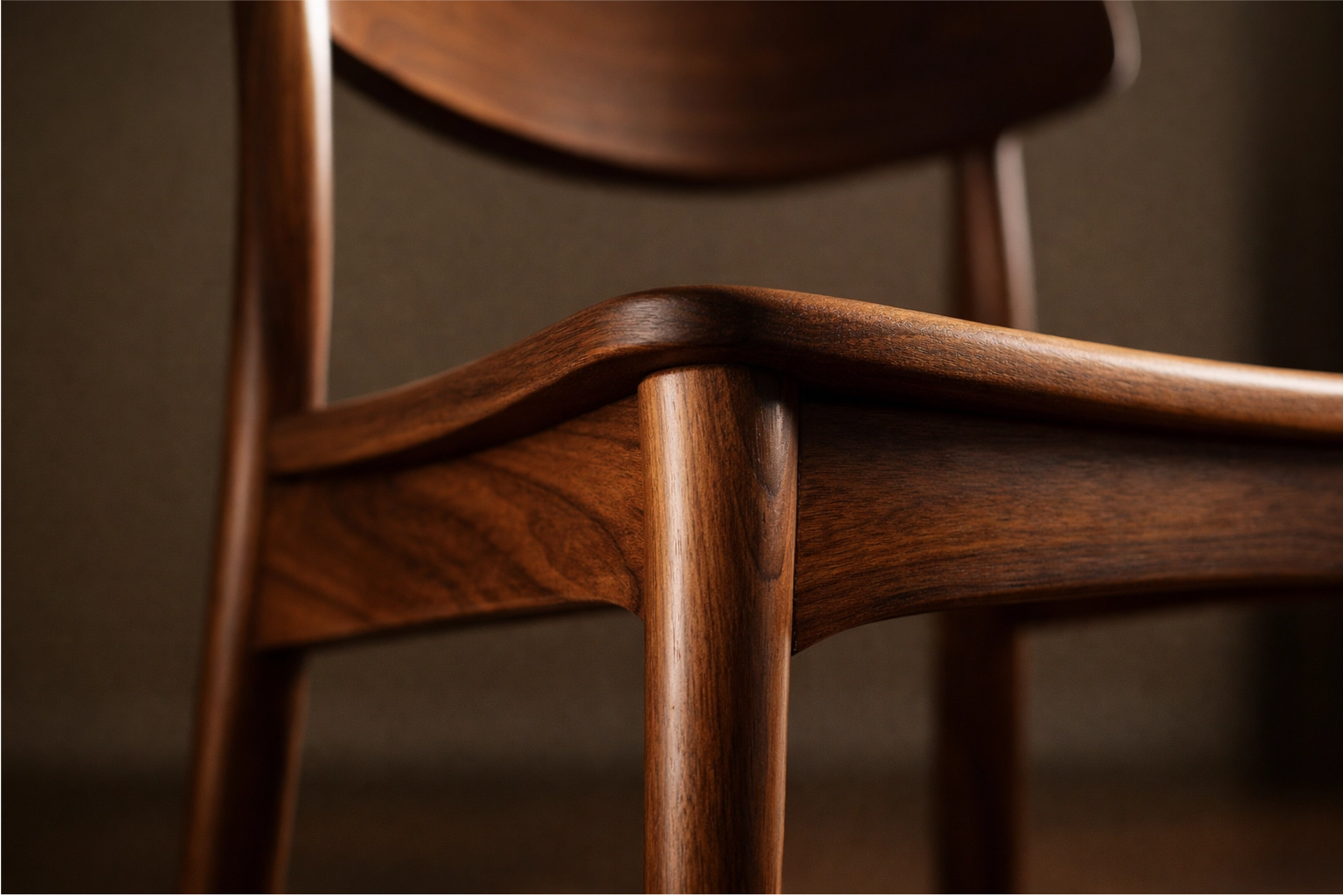 A close-up of a classic MCM dining chair, highlighting its tapered legs and curved wooden back