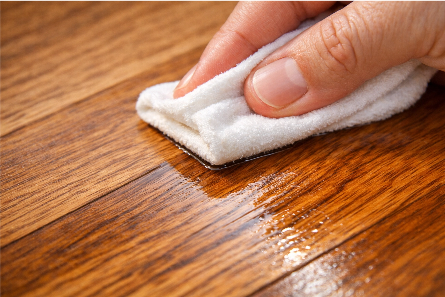 a hand applying a clear sealer to a clean teak tabletop with a cloth